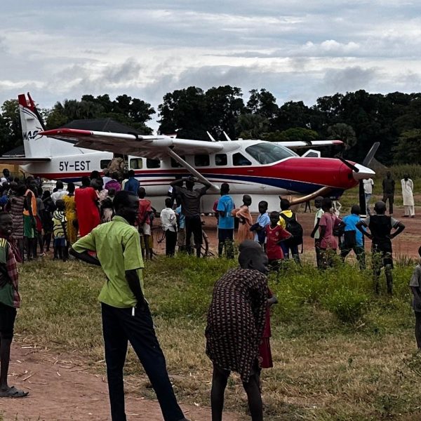 Kuva 5B Monesti lentokoneen saapuminen on suuri tapahtuma kylässä ja kaikki kynnelle kylenevät tulevat sitä ihmettelemään. Erityisesti nuoret pojat ovat haltioissaan lentokoneista.